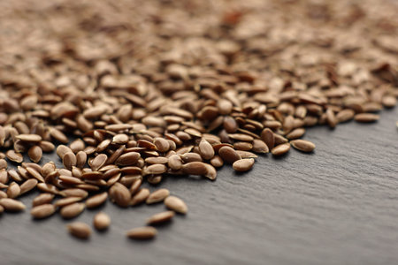 Raw organic flaxseeds.Close up of Linum usitatissimum seeds on dark stone background.Super seeds. ...