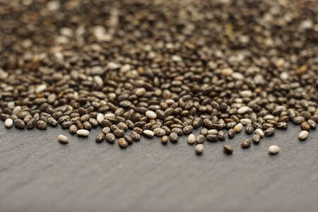 Raw organic chia seeds.
Close up of Salvia hispanica seeds on dark stone background.
Super seeds.  Selective focus. 
Healthy  food concept.の写真素材