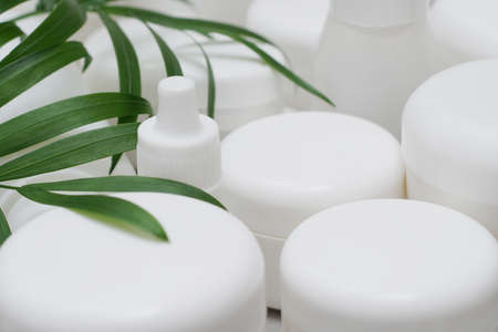 Mock-up.Empty bottles and jars for gel, lotion, cream.White plastic containers for skincare products without labels.Unbranded beauty product package.Green leaves.Cosmetic, pharmacy concept.の写真素材