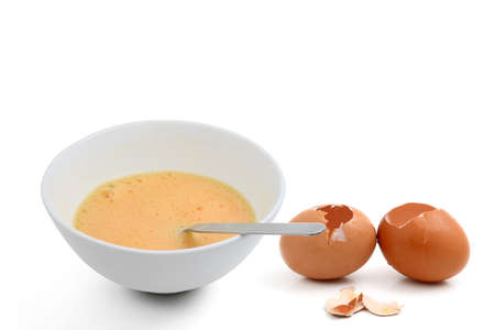 Beaten egg yolks in cup with eggshellの写真素材