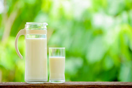 milk jug with glass on table with nature backgroundの写真素材