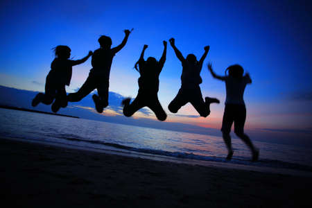 Silhouette of young friends jumping on the Pattaya beach and  backdrop of sunset over the sea in Thailandの写真素材