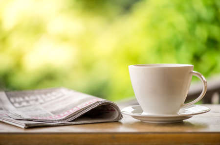 good morning coffee cup with news paper on nature green background in gardenの写真素材
