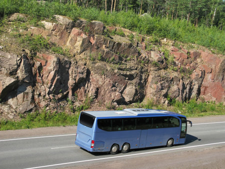 blue tourist bus on rocky highwayの写真素材