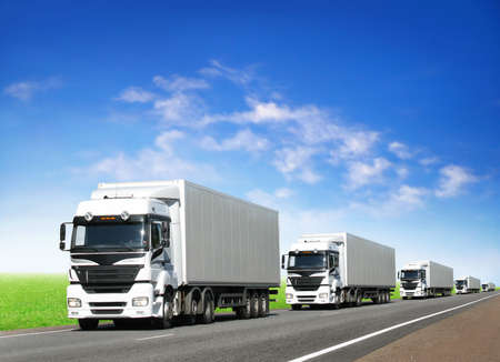 caravan of white trucks on country highway under blue sky caravan of white trucks on country highway under blue sky