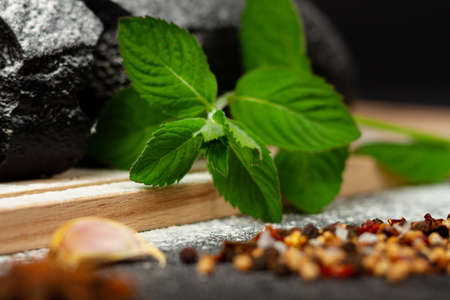 fresh black rye bread on a cutting board with seasonings sprinkled with flour on a black wooden tableの写真素材