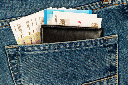 black wallet and banknotes sticking out of blue jeans pocket