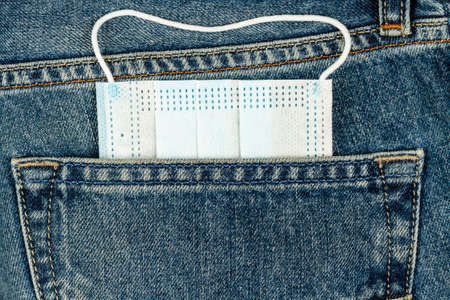 medical mask sticks out of blue jeans pocketの写真素材