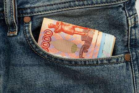 banknotes sticking out of blue jeans pocketの写真素材