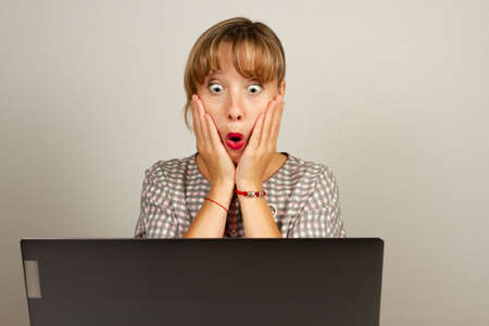 beautiful young girl was very surprised working in the office at the computerの写真素材