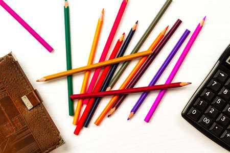 colored pencils and brown leather diary lie on a white wooden tableの写真素材