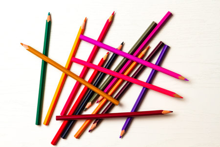 many colored sharpened pencils lie on a white wooden table