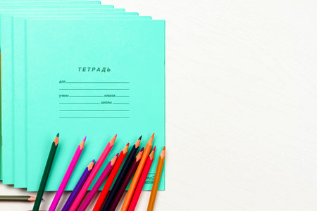 colored pencils and school notebooks lie on a white wooden table lettering notebook for a student of school class 12 sheetsの写真素材
