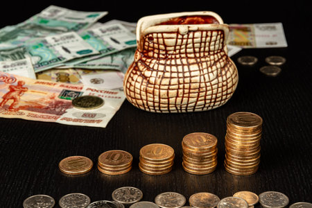 stack of metallic gold coins and paper money and piggi bank lie on a black wooden table