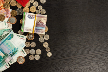 a lot of Russian metal coins and paper money lie on a black wooden table