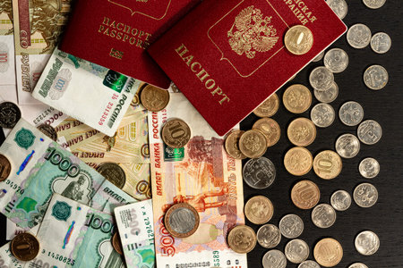 coins and paper money and two international passports lie on a black wooden table inscription...