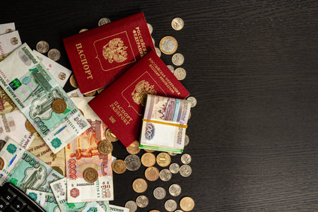 coins and paper money and two international passports lie on a black wooden table inscription...