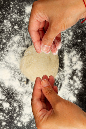 girl chef sprinkles flour on black wooden kitchen table to make homemade dough