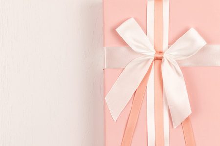 pink gift box with silk bright bow and ribbon on white wooden tableの写真素材