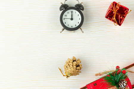 alarm clock, santa claus sleigh, gift box, golden Christmas tree cone on a white wood background...