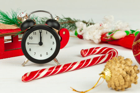 santa claus sleigh, alarm clock, santa claus staff, golden christmas tree cone and boxes with gifts on a white wood background with gold veinsの写真素材