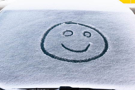 image of a smiling face in the snow on the windshield of a car on a frosty winter dayの写真素材