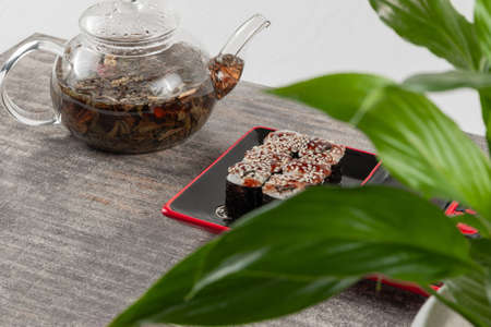teapot glass teapot with herbal tea and rolls with eel and sesame seeds on gray granite stoneの写真素材