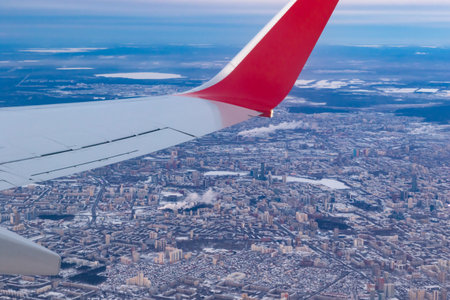 a view of the winter city from a height of flight from the window of an airplane with a silvery red...