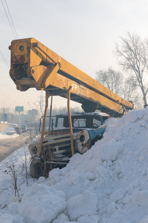 old broken rusty truck crane with yellow boom covered with snow on a cold winter dayの写真素材