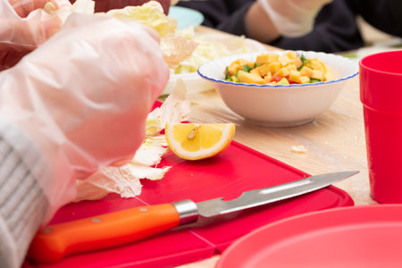children in a school class at a labor lesson prepare a vegetable salad. parts of hands close-up. selective focusの写真素材