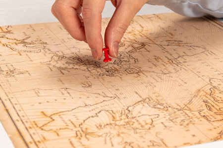 female hand shows the place of travel on the world map on the background of a white wooden table....