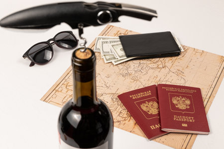 the neck of a bottle of red wine with a corkscrew in the cork, a map of the world, two passports, money in a black leather wallet and sunglasses. selective focus. inscription - passport Russian Federationの写真素材