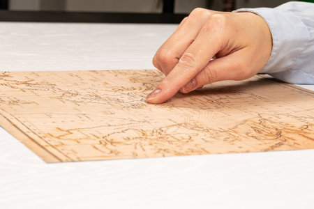 female hand shows the place of travel on the world map on the background of a white wooden table....
