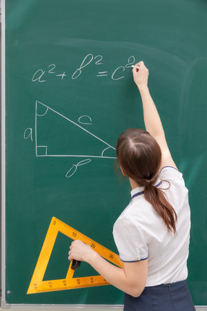 school teacher young woman in the class at the blackboard draws a triangle with a ruler. portrait....