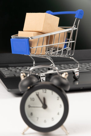 metal chrome cart and alarm clock on the background of a black laptop on a white wooden table. selective focusの写真素材