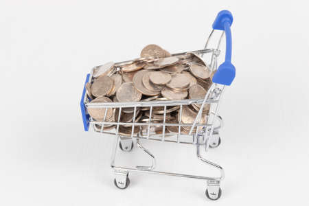 metal chrome shiny shopping trolley on wheels with nickel plated coins isolated on white background. close-upの写真素材