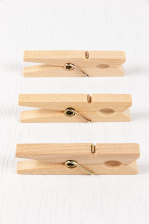 three wooden clothespins with a metal spring on the background of a white wooden table. close-up....