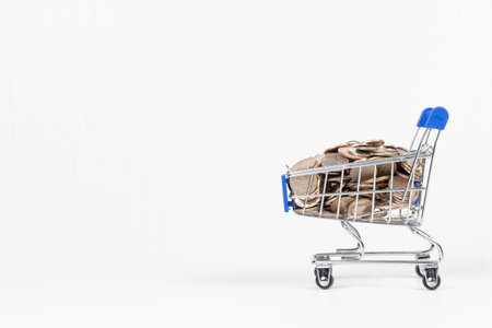 metal chrome shiny shopping trolley on wheels with nickel plated coins isolated on white background....