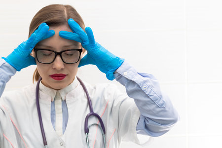 Beautiful young doctor woman in medical gloves and glasses with a stethoscope in a hospital on a...