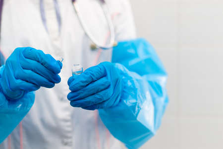 Doctor's hands in rubber medical gloves hold an ampoule of medicine in a hospital during the coronavirus pandemic. Selective focus. Close-upの写真素材