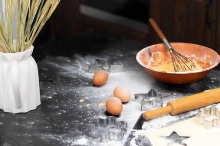 Rolled out puff pastry and molds for baking cookies, eggs, wooden rolling pin, spilled flour, a jug...