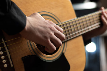 Hands of a musician playing an acoustic guitar with metal strings. hobby. musical instruments....