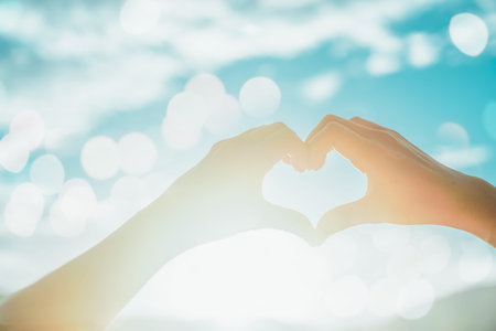 Woman hand do heart shape on blue sky  and bokeh background.の写真素材