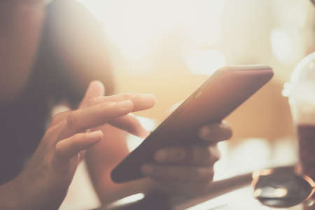 Woman hand using smartphone or tablet to do business, financial social network  in cafe backgroundの写真素材