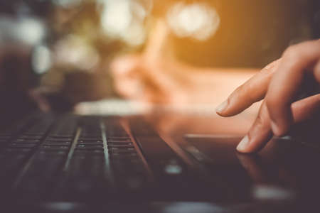 Woman hand using laptop to work and study on vintage soft color tone bokeh background.Technology social media financial business concept.の写真素材