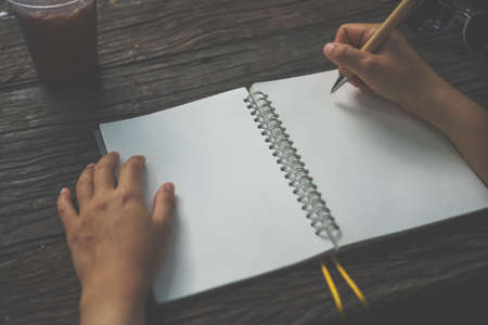 Copy space of woman hand writing down in white notebook with sun light background.の写真素材