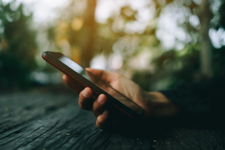 Woman hand using smartphone or tablet to do business, financial social network  with mountain view nature backgroundの写真素材