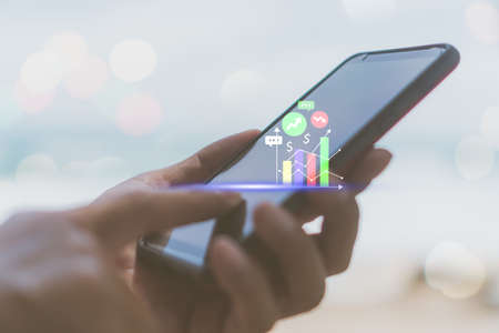 Woman hand using smartphone or tablet to do business, financial or trading stock forex market  with beach nature backgroundの写真素材