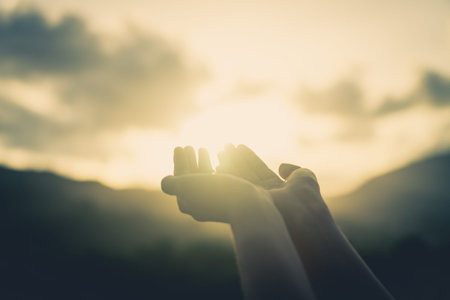 Woman hands place together like praying in front of nature green  background.の写真素材