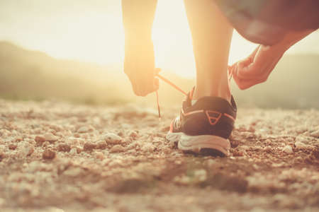 Woman wear running shoe on to walking and running on nature green background.Health exercise concept.の写真素材